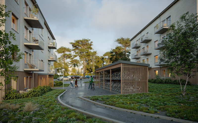 Två vita bostadshus med ett cykelgarage och några människor mellan.