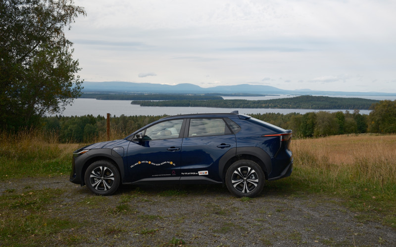 En bil parkerad på en grusväg intill sjö