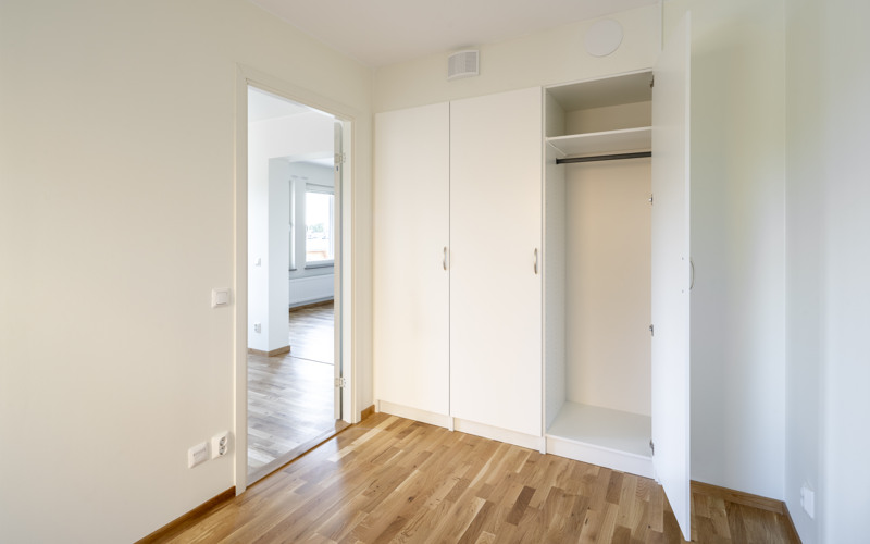 Ett tomt rum med en garderob och en dörr.